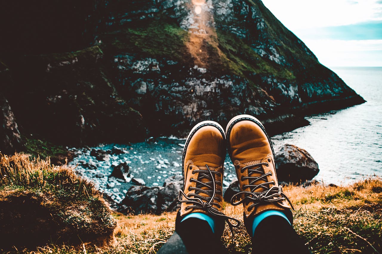 about-us A person relaxes in hiking boots overlooking stunning coastal cliffs and ocean view.